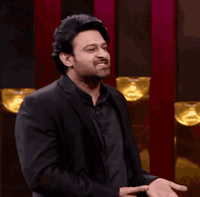 a man in a suit and black shirt is smiling