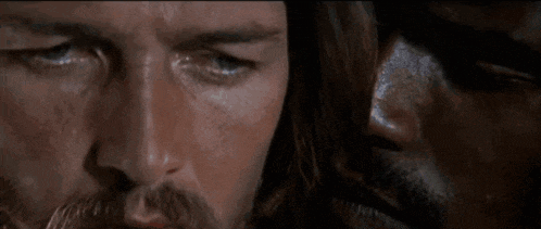 a close up of a man with a beard looking at another man