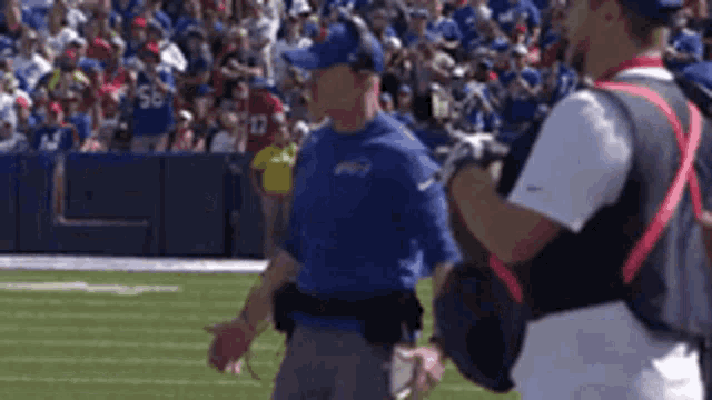 a man in a buffalo bills uniform talks to another man on the field