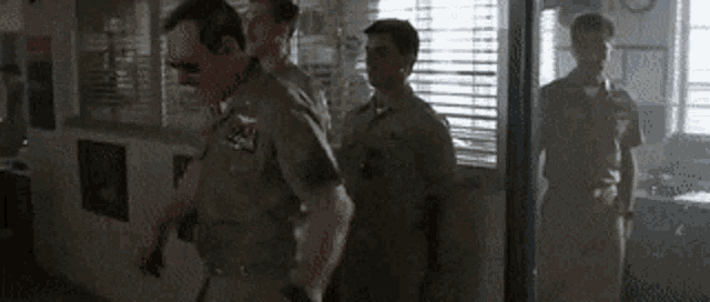 a group of police officers are walking through a doorway in a room .