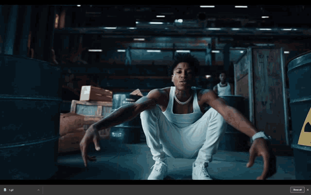 a man in a white tank top is squatting down in front of some barrels