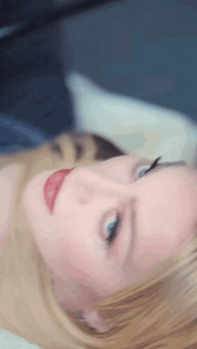 a close up of a woman 's face with blue eyes and red lips