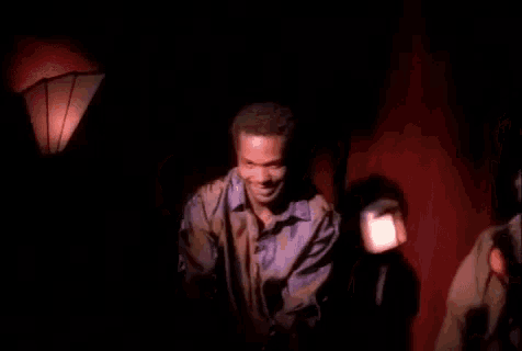 a group of people are standing in a dark room with a red curtain .