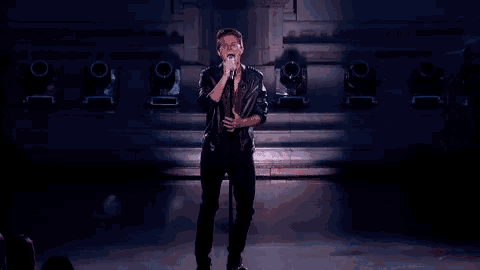 a man is singing into a microphone on stage .