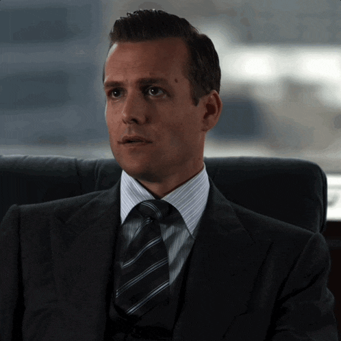 a man in a suit and tie is sitting in an office chair