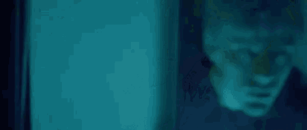 a close up of a person 's face in a dark room with a blue light behind them .