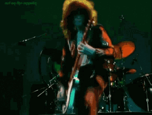 a man is playing a guitar on a stage with a green light behind him