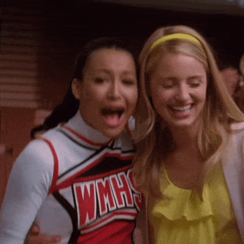 two cheerleaders wearing wmhs uniforms are laughing together