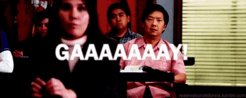 a group of people are sitting at a table with the words gaaaaaaay written on the screen