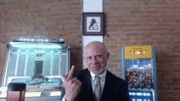 a man in a suit and tie is making a middle finger sign in front of a jukebox .