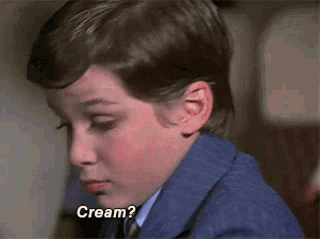 a young boy in a suit and tie is asking for cream .