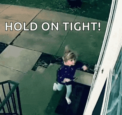 a little girl is running towards a door with the words `` hold on tight '' written on the screen .