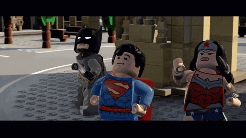 lego batman superman and wonder woman are standing on a street