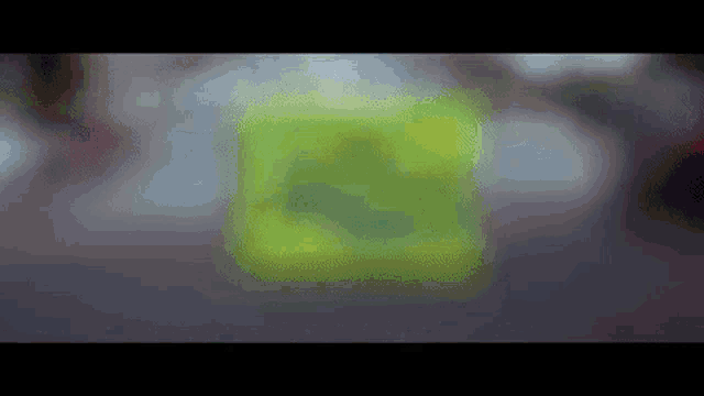 a blurry picture of a green cube on a table