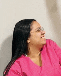 a woman wearing glasses and a pink scrub top is smiling and looking to the side .