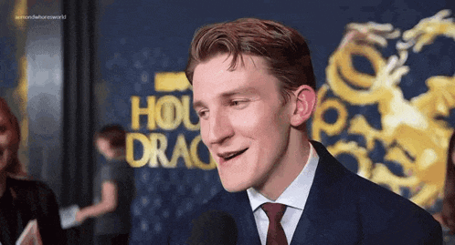 a man in a suit and tie is standing in front of a microphone and smiling .