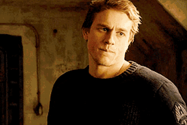 a man wearing a black sweater is standing in a dark room
