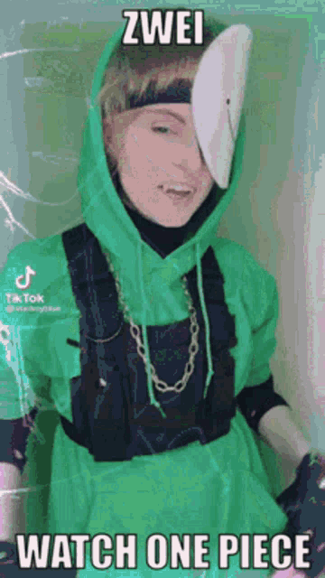 a person wearing a green hoodie and a white mask with the words `` zwei watch one piece '' on it .