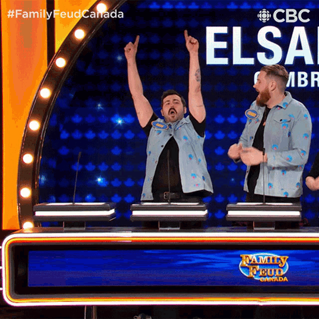 a man with his arms in the air stands in front of a family feud sign