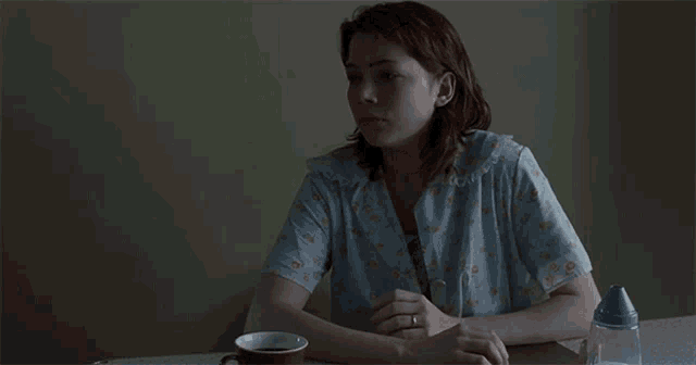 a woman sits at a table with a cup of coffee
