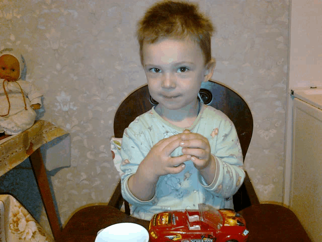 a little boy is sitting in a chair with a bag of m&ms in front of him
