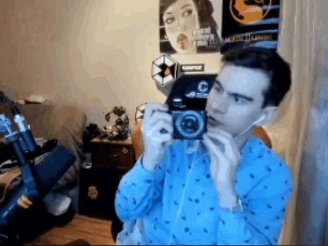 a man in a blue shirt is holding a small camera