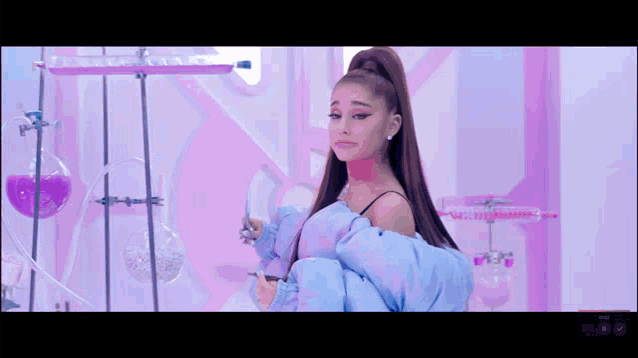 ariana grande is wearing a blue jacket and standing in front of a pink wall