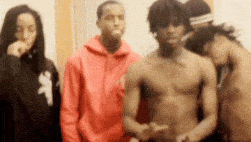 a group of young men are standing next to each other and one of them is shirtless .
