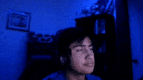 a man in a blue shirt is standing in a dark room