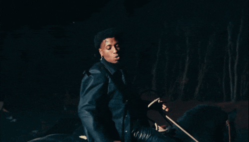 a man in a black jacket rides a black horse