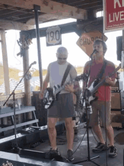 two men playing guitars in front of a sign that says 190 church