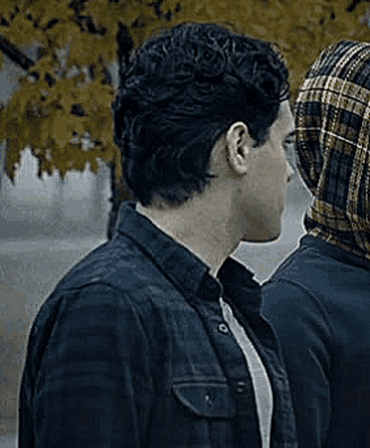 a man in a plaid shirt is standing next to another man in a plaid hoodie .