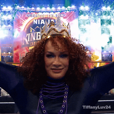 a woman wearing a tiara stands in front of a sign that says " queen of the ring "