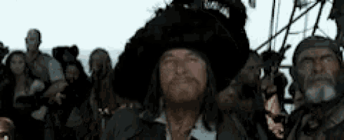 a man in a pirate hat is standing in front of a crowd .