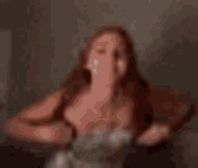 a blurry picture of a woman in a white dress standing in a dark room .