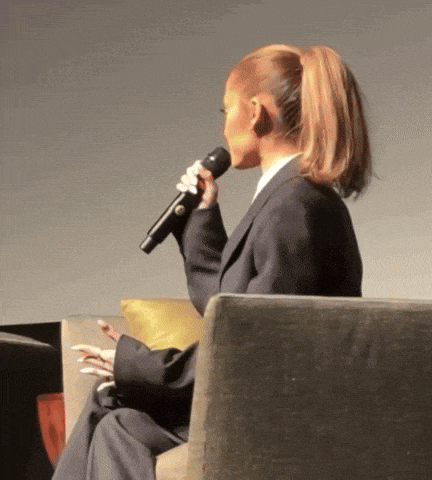 a woman in a suit is holding a microphone