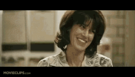 a woman is smiling in a kitchen in a movie clip .