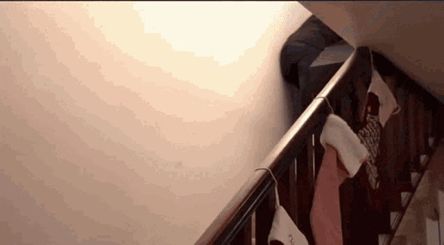 a person is walking down a set of stairs with christmas stockings hanging on the railing .