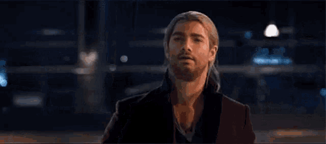 a man in a suit is holding a hammer in his hand and looking at it .