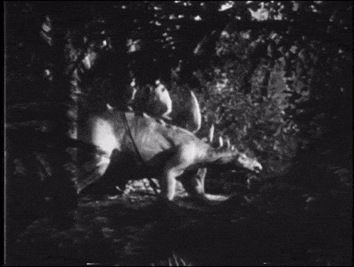 a black and white photo of a dinosaur walking through a forest
