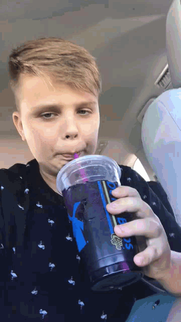 a young boy is drinking from a cup that says smoothies on it