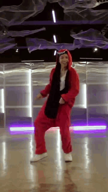 a woman in a red jumpsuit is dancing on a dance floor .