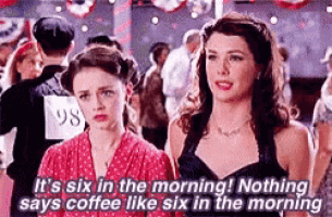 two women are standing next to each other in a crowd . one of the women is talking about coffee .