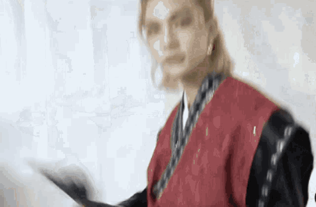 a man in a red kimono is holding a black sword in his hand .