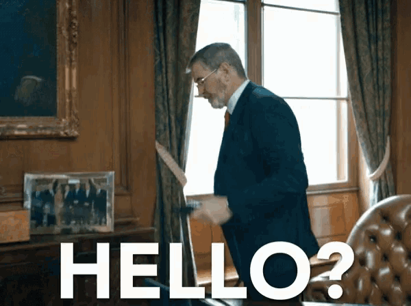 a man in a suit is standing in front of a window with the words hello written on the wall