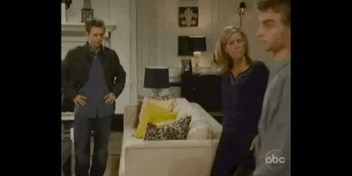 a group of people standing in a living room with abc written on the bottom right corner