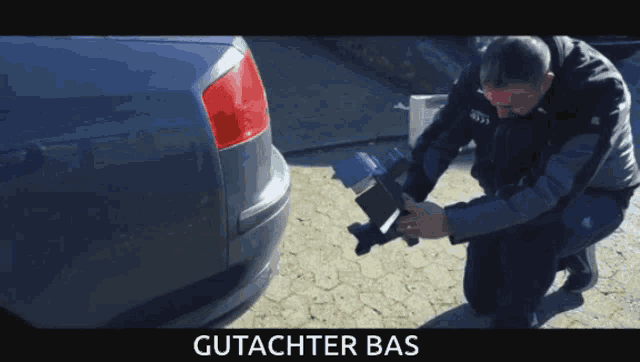 a man is kneeling in front of a car and the word gutachter bas is on the bottom right