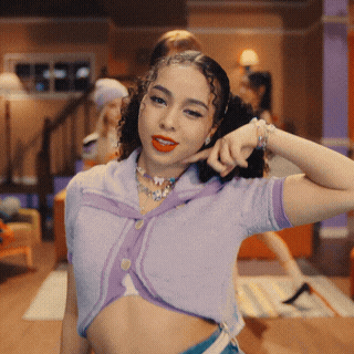 a woman wearing a purple crop top is making a funny face