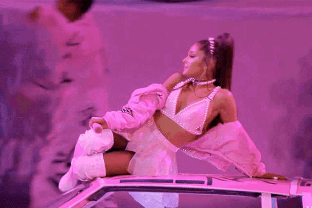 ariana grande in a pink outfit is laying on top of a pink car