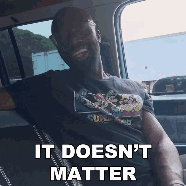 a man wearing a super mario shirt is sitting in the back seat of a car